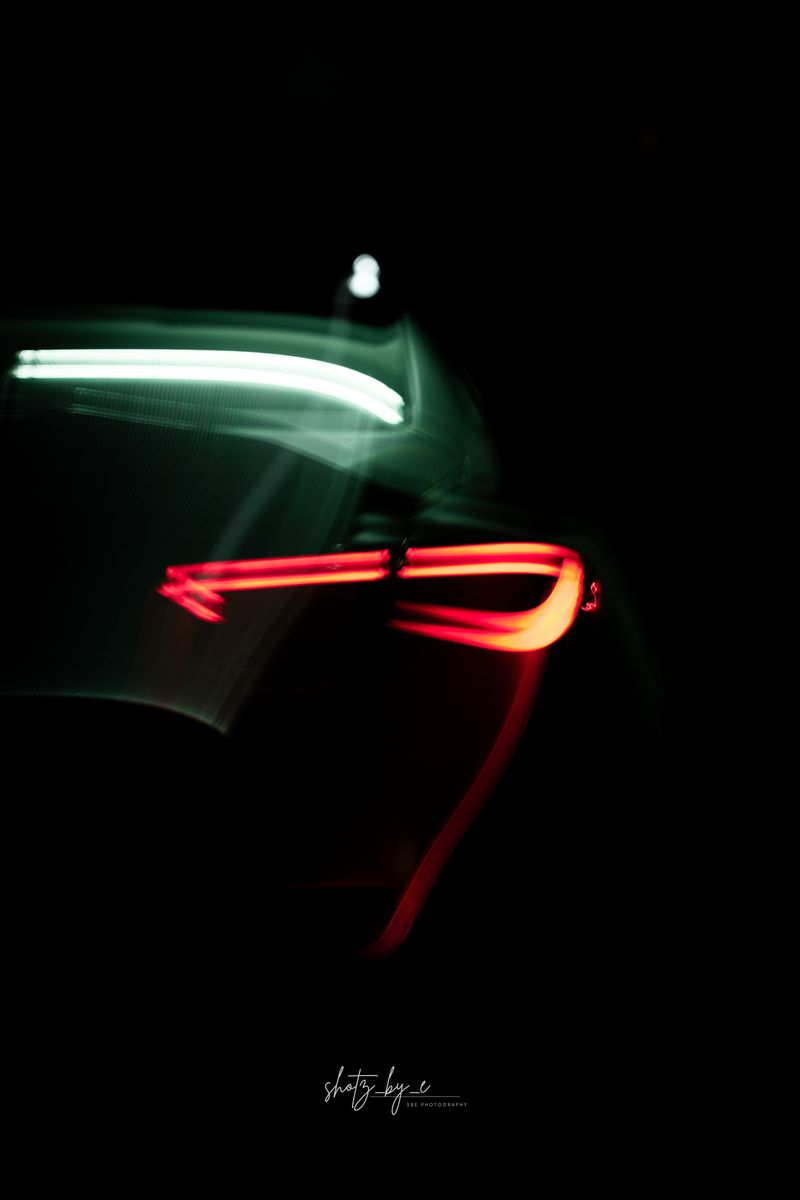 Rear of a Supra with red tail light trails at night