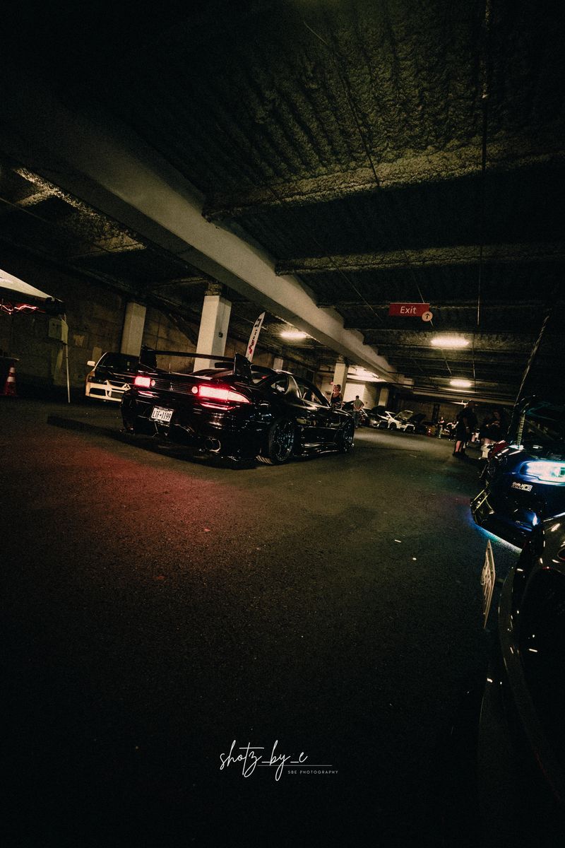 Black car facing away under an exit sign in a garage